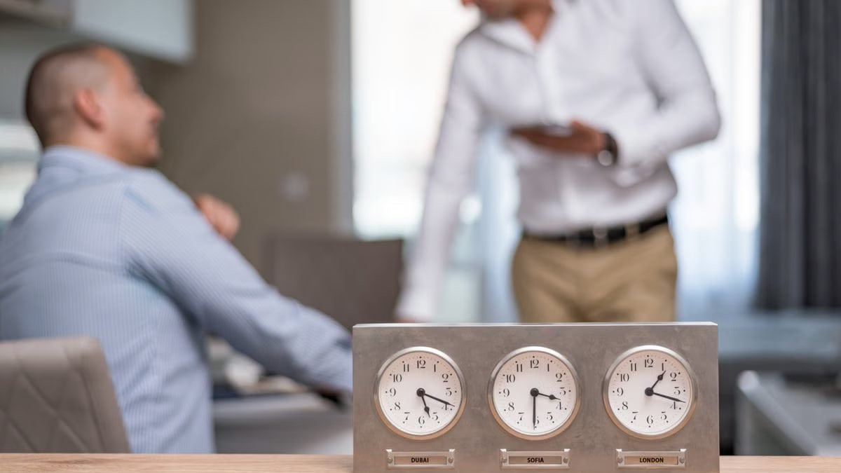 Two businessmen in an office with clocks displaying Dubai, Sofia, London time.